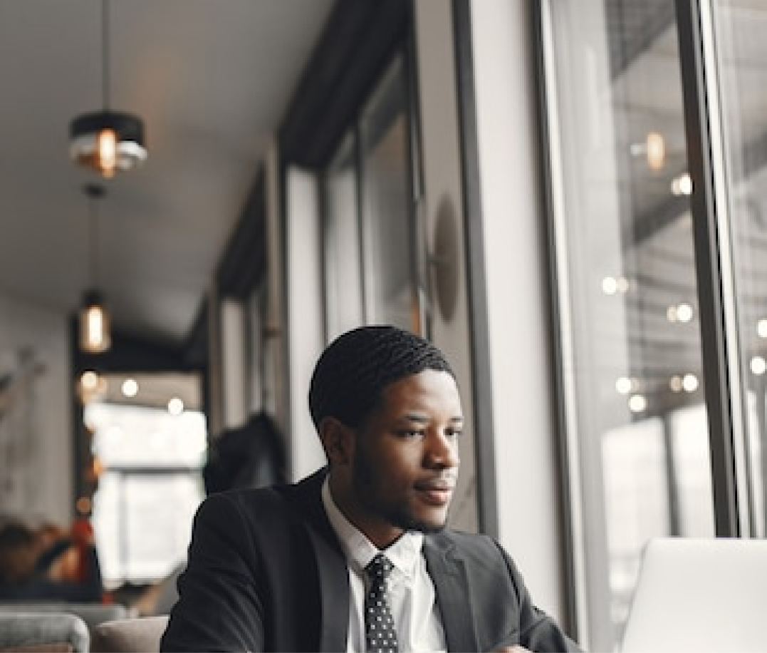 A black man on a black suit, seated close to the window