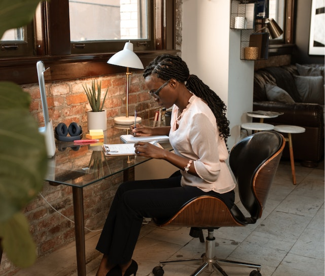 A black lady on braids seated before a table