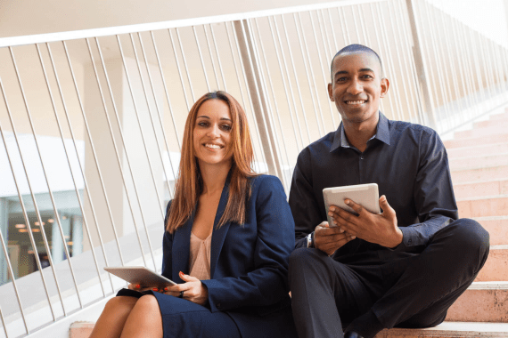 colleagues-holding-tablet-computers-sitting-stairs